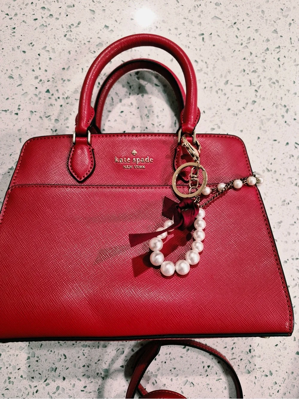 This red satchel is a Kate Spade New York Madison Saffiano Leather